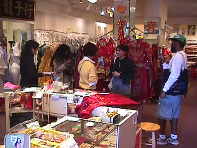 Photo Phloor on the Chinatown photo walk: five of them talking and shooting among the racks of red qipao in the shop they pinned to the circle.