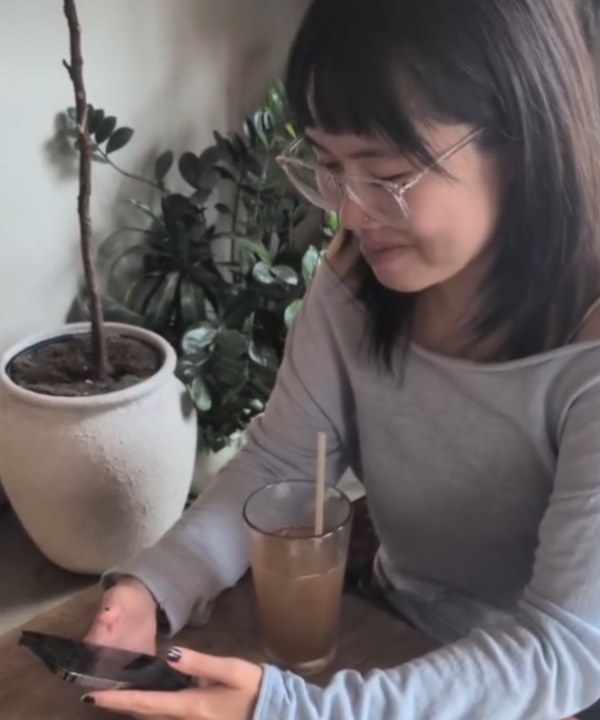 A maker at a cafe table, phone in hand, placing pages in the zine editor